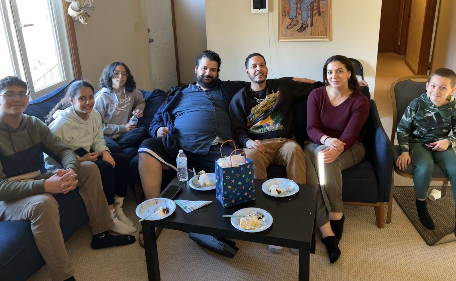 Family and friends gathered on sofas around a coffee table in a living room.